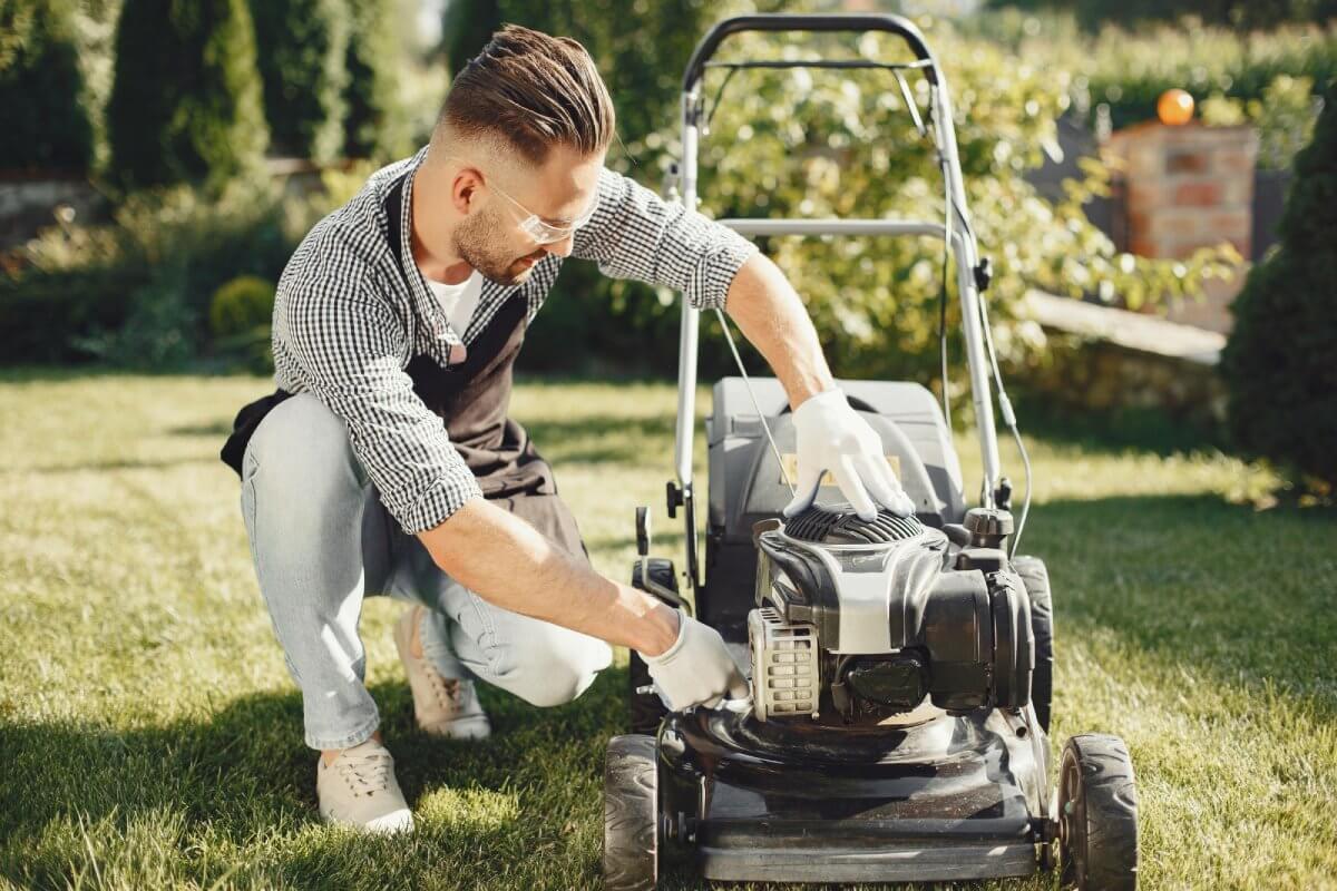 Mężczyzna sprawdzający kosiarkę po pracy